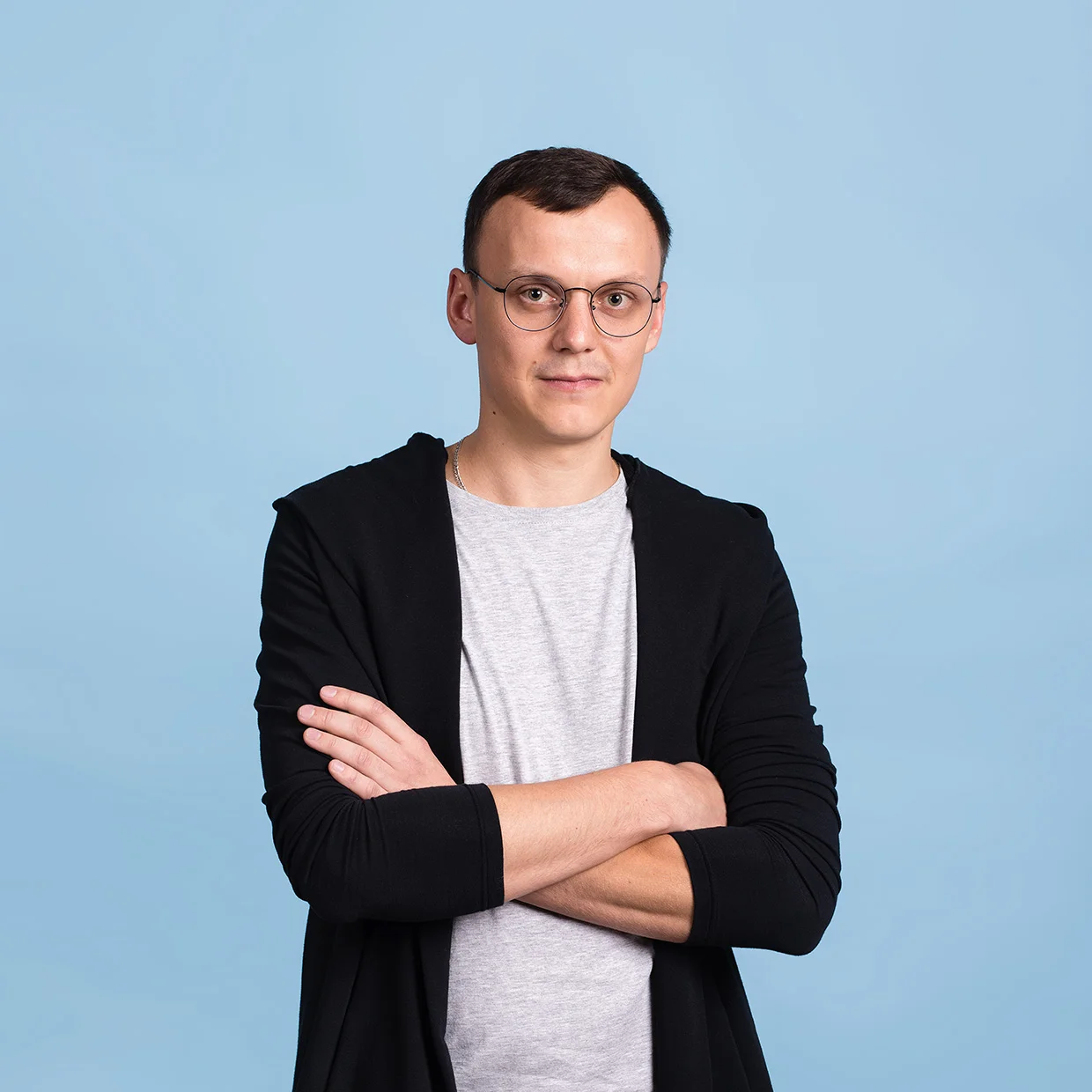 Уверенный в себе молодой человек в очках и повседневной одежде на синем фоне